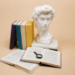 Estátua, livros e lupa posicionados, representando o estudo das ciências humanas.
