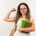 Jovem menina segurando livros e fazendo um muque, demonstrando determinação para a redação do ENEM.