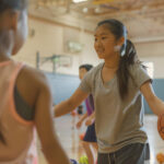 Estudante em uma quadra, jogando basquete com seus colegas, demonstrando que a saúde física e mental impactam o aprendizado de alunos.
