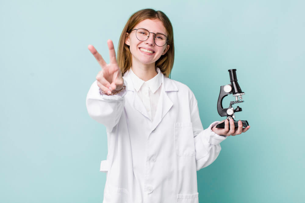 Jovem segurando um microscópio, representando o trabalho de uma pessoa que está buscando entender o que se estuda em química.